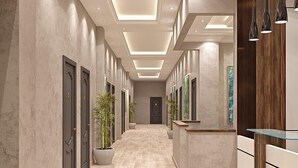 Eine moderne Hotelhalle mit einer langen Korridor, Holzboden und einer Rezeption mit Glastisch.