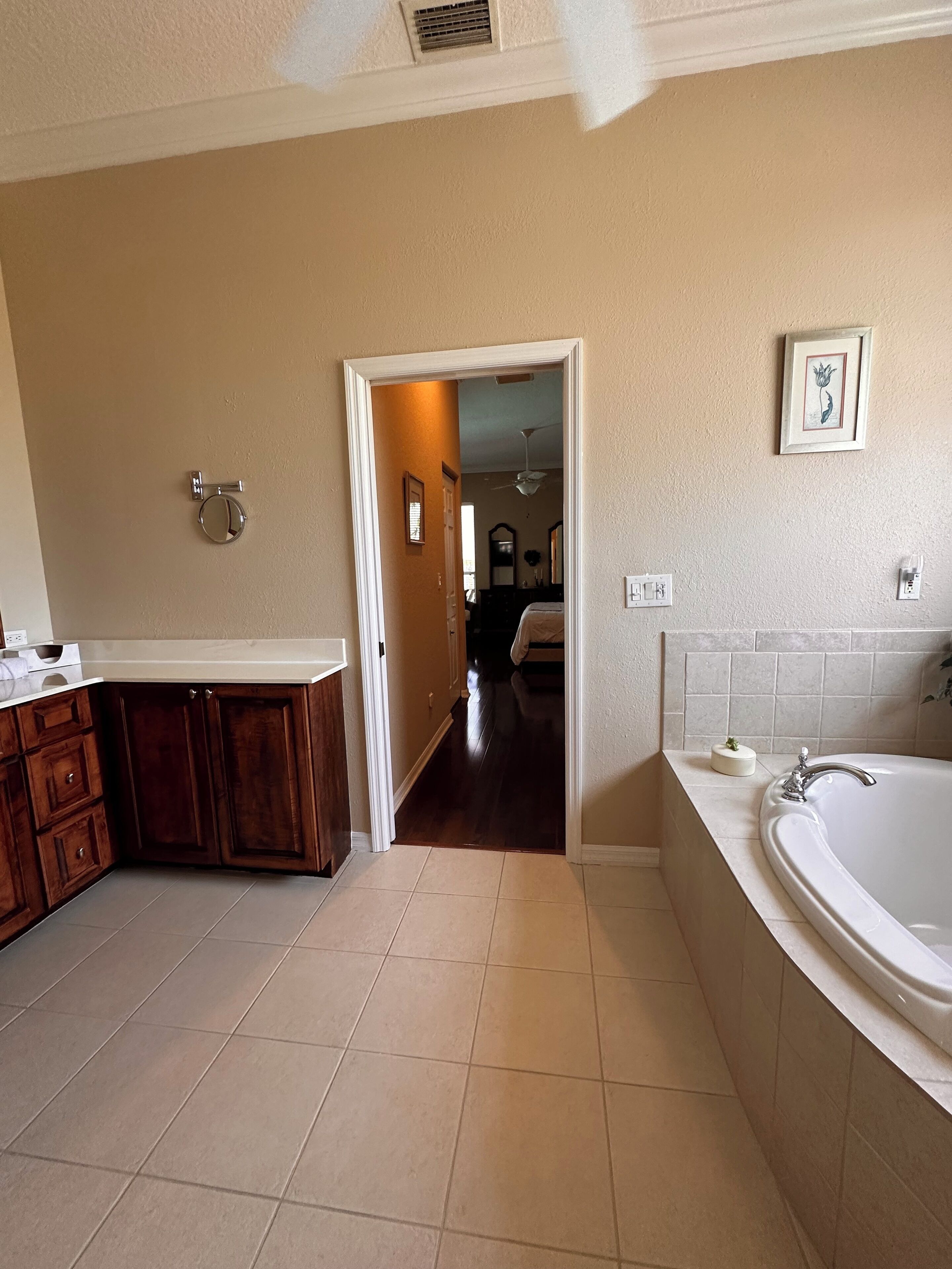 A bathroom with a bathtub, a sink, and a vanity with cabinets. There is a door leading to another room.