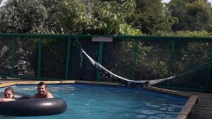 Una piscina con dos personas dentro de un flotador inflable negro y otro flotador inflable amarillo.