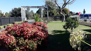 Un jardín con un pérgola, un árbol y diversas plantas.