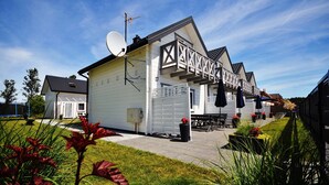 Een wit gebouw met een schotelantenne, een overdekt terras en een hekwerk.