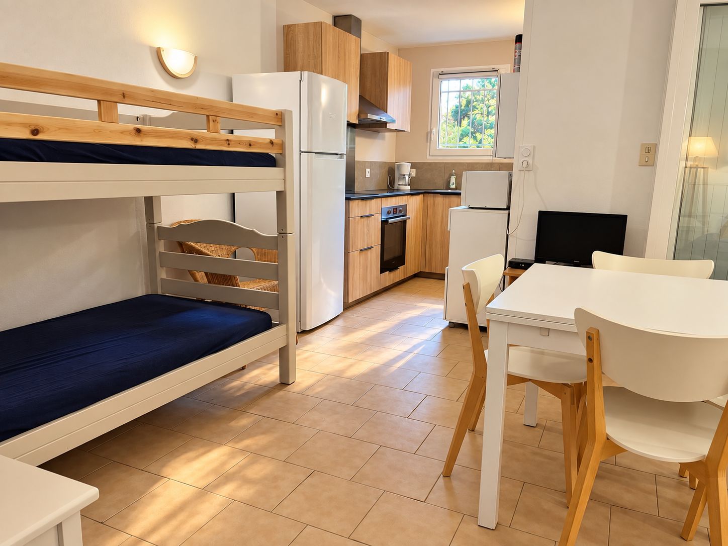 A compact room with bunk beds, a kitchenette, a dining area, and a window with a view.