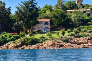 A coastal property with a stone building, a grassy lawn, and a rocky shoreline.