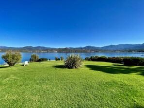 Une zone herbeuse offrant une vue dégagée sur un lac et des montagnes en arrière-plan.