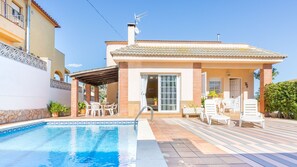 A two-story house with a swimming pool, outdoor seating, and a covered patio area.