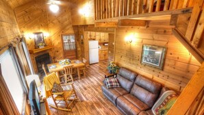 A wooden cabin interior with a dining area, sofa, and kitchen. - Three Bears Cabin- Enjoy the scenery around you with a peaceful view (Sautee Nacoochee)