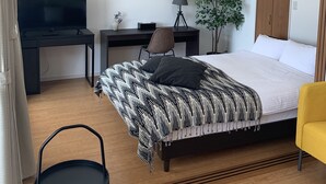 Un dormitorio moderno con cama, escritorio, silla, televisor y armario.