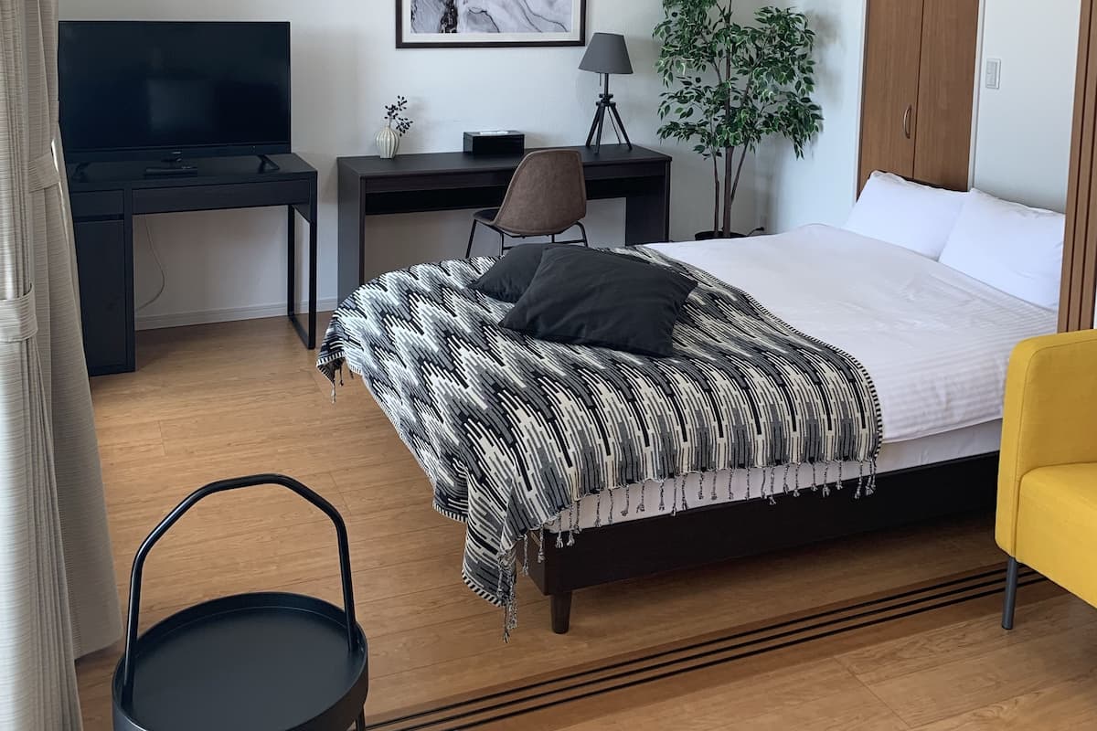 A modern bedroom with a bed, a desk, a chair, a TV, and a wardrobe.