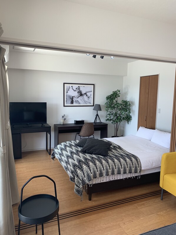 A modern bedroom with a bed, a desk, a chair, a TV, and a wardrobe. - European House Reisen (Fukuoka)
