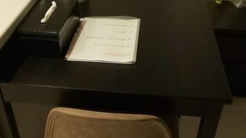 A small, dark-colored table with a single chair, a white mug, and a book on it.