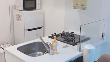 Una kitchenette compacta con lavamanos, estufa, microondas y refrigerador.