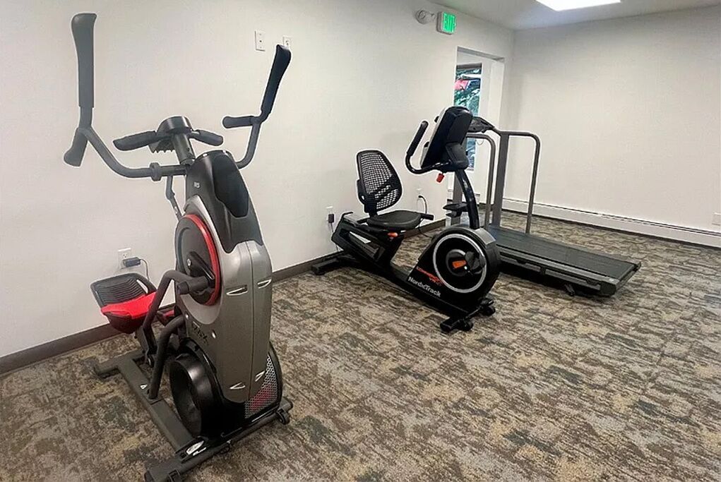 A gym with stationary bikes, a treadmill, and a chair.