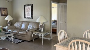 A living room with a sofa, two lamps, a coffee table, and a dining table with chairs. - VILLA THERESA -Tropical Paradise home Perfect for Family or a Romantic Vacation (Cape Coral)