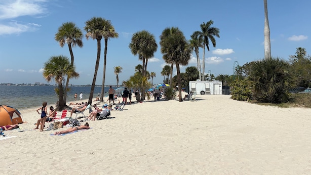 A beach with palm trees, a tent, and a white RV. - VILLA THERESA -Tropical Paradise home Perfect for Family or a Romantic Vacation (Cape Coral)