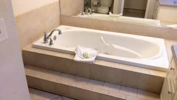 A bathroom with a large bathtub, a sink, and a toilet.