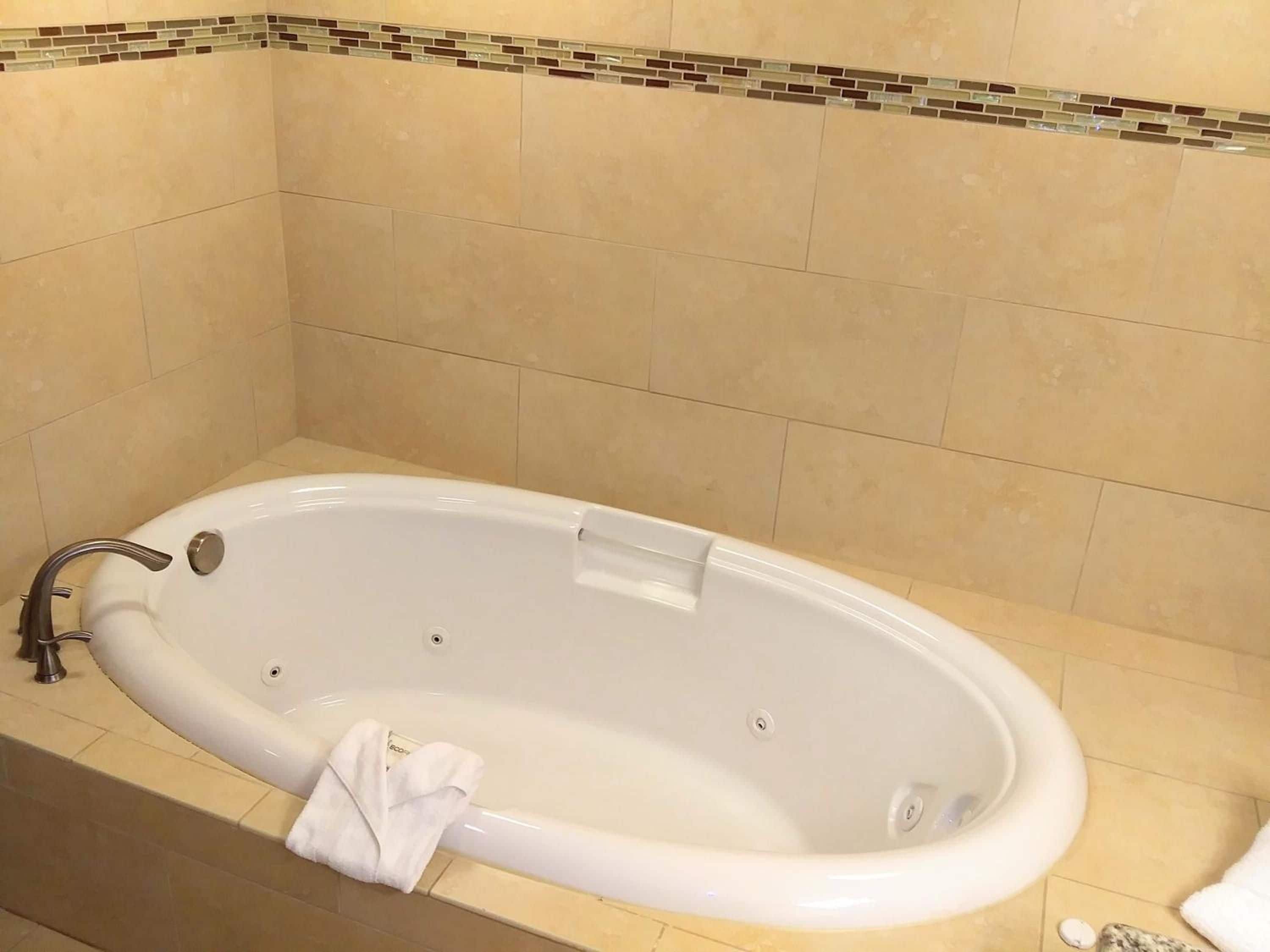 Eine weiße Badewanne mit einem Wasserhahn, einem Handtuch und einer kleinen Flasche daneben.