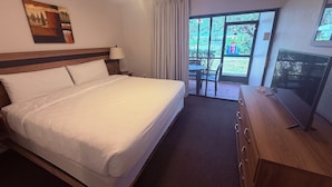 Habitación de hotel con una cama grande, un escritorio con televisor de pantalla plana, una ventana con vistas al exterior y un cuadro en la pared.