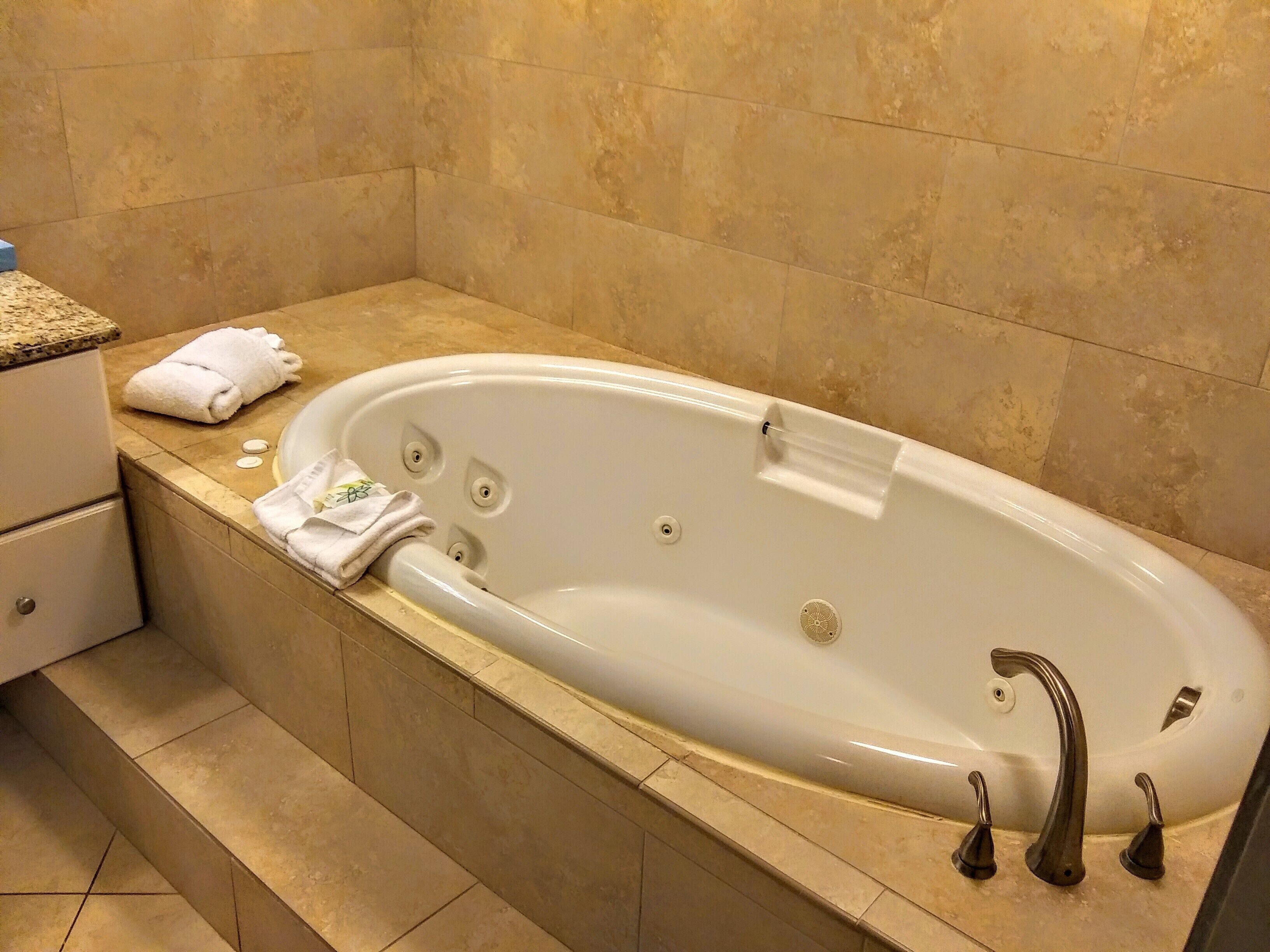 A bathroom with a white bathtub, a towel, and a sink.