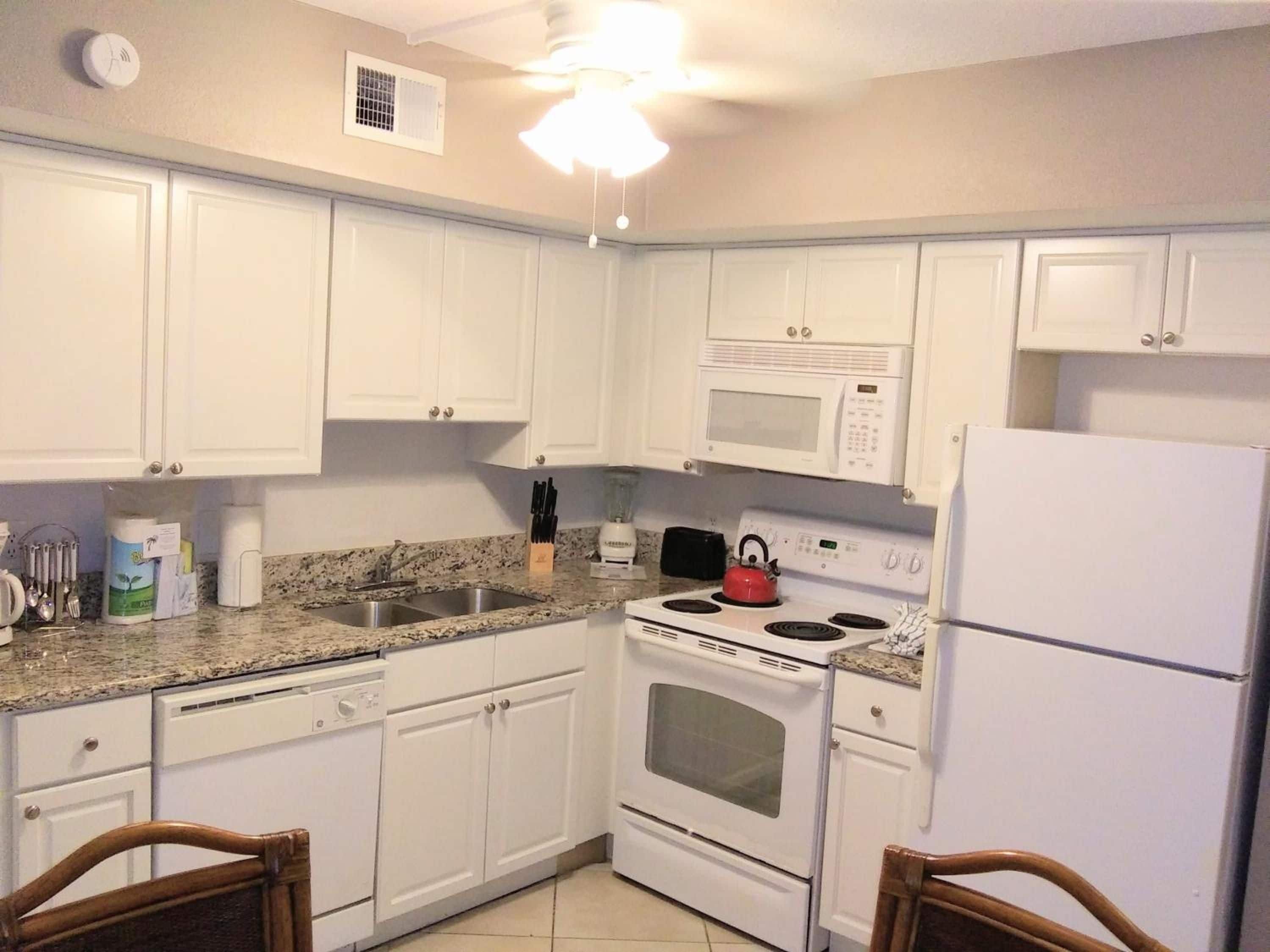A kitchen with white cabinets, a microwave, a stove, and a refrigerator.
