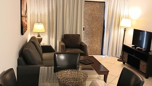Una sala de estar moderna con una mesa de comedor de vidrio, sofás de cuero y un televisor de pantalla plana.