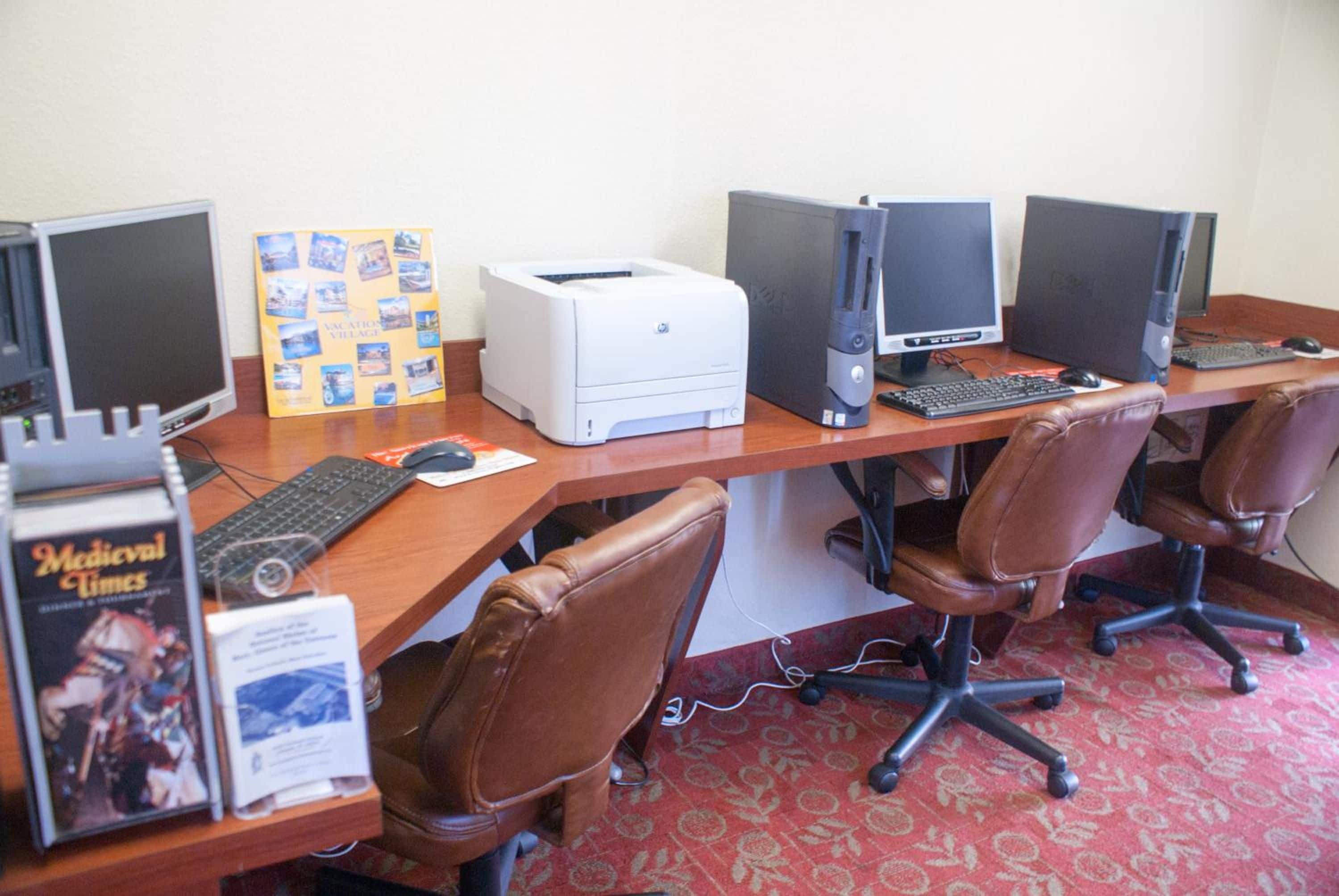 Un laboratorio informatico con diversi computer desktop, sedie e una stampante.