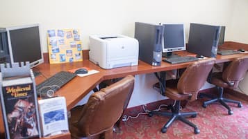 Un laboratorio de computadoras con varias computadoras de escritorio, sillas e impresora.