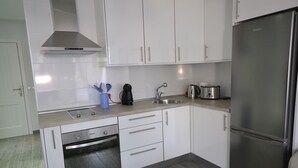 Una cocina moderna con armarios blancos, electrodomésticos de acero inoxidable y horno empotrado.