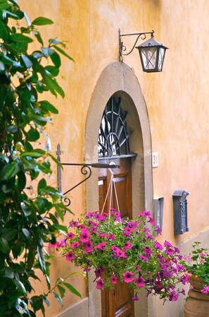 Ein Gebäudeeingang mit schmiedeeisernem Tor, einer hängenden Laterne und einem blumengeschmückten Korb.