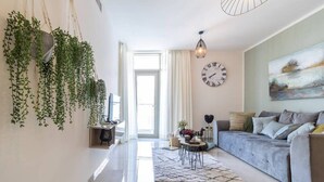 A modern living room with a grey sofa, a coffee table, and hanging plants.