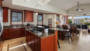 A spacious kitchen with a large island, wooden cabinets, and a dining area with wicker chairs.