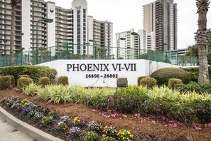 A sign for 'PHOENIX VI-VII' with a mailbox and a landscaped garden with various plants.