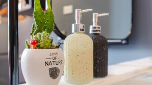 A cactus plant in a white pot with the text "Love of Nature" and a soap dispenser on a marble surface. - The Poppy Villa & Hotel (Hanoi)
