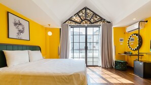 A hotel room with a large bed, a vanity with a mirror, and a view of the outside through a glass door. - The Poppy Villa & Hotel (Hanoi)