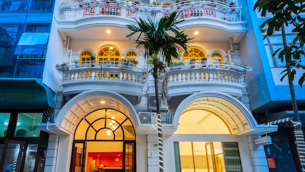 A multi-story building with balconies, arched windows, and a central palm tree. - The Poppy Villa & Hotel (Hanoi)