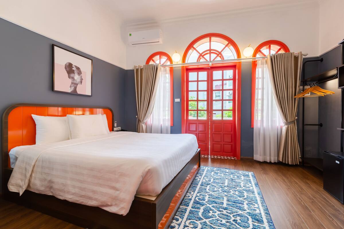 A bedroom with a bed, a red door, and a wardrobe.