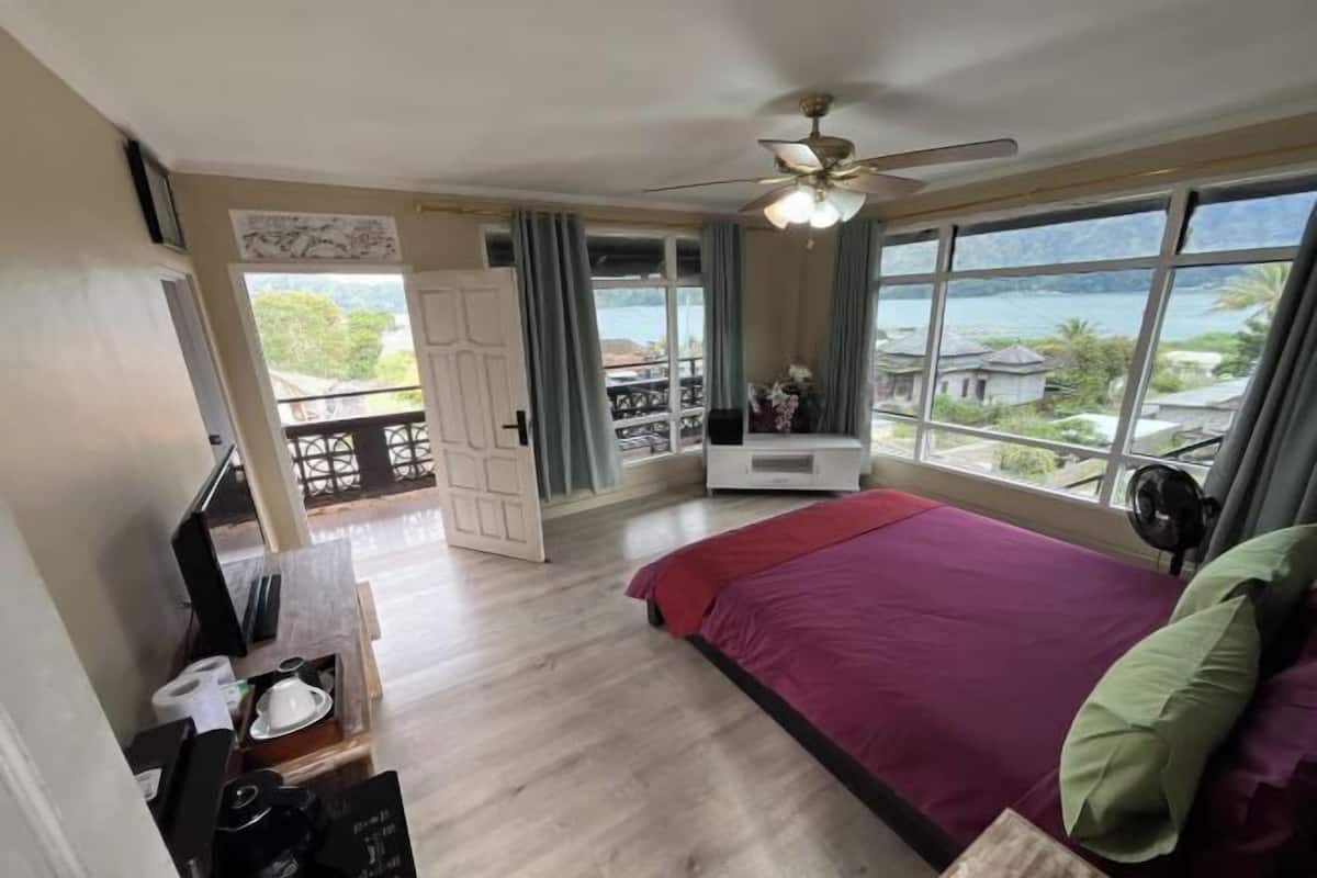 Un dormitorio con cama, ventilador de techo, ventana con vistas y balcón.