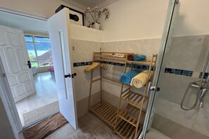 Un baño con ducha, perchero para toallas y vista al océano a través de una puerta.