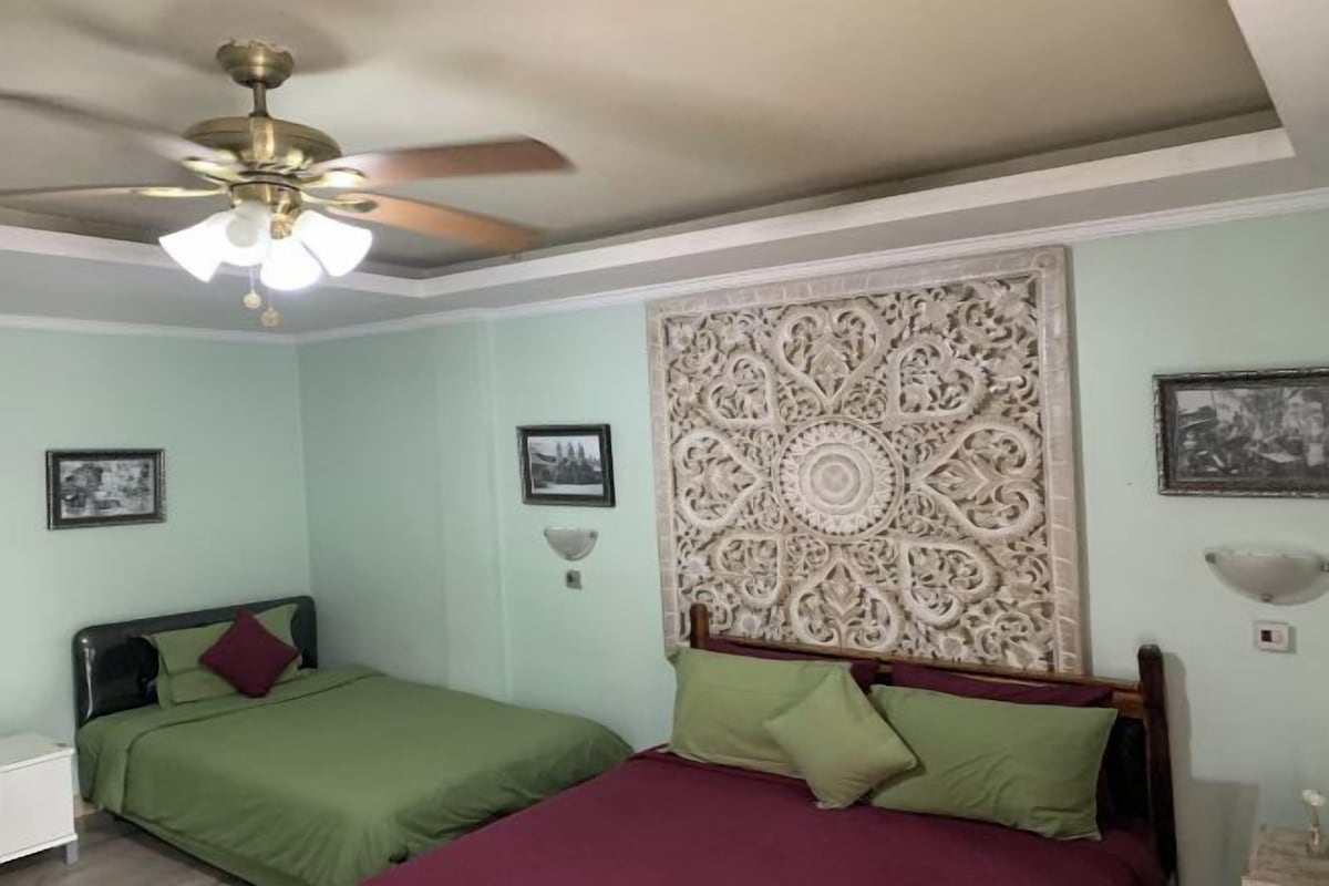 A bedroom with two beds, a ceiling fan, and decorative wall paneling.