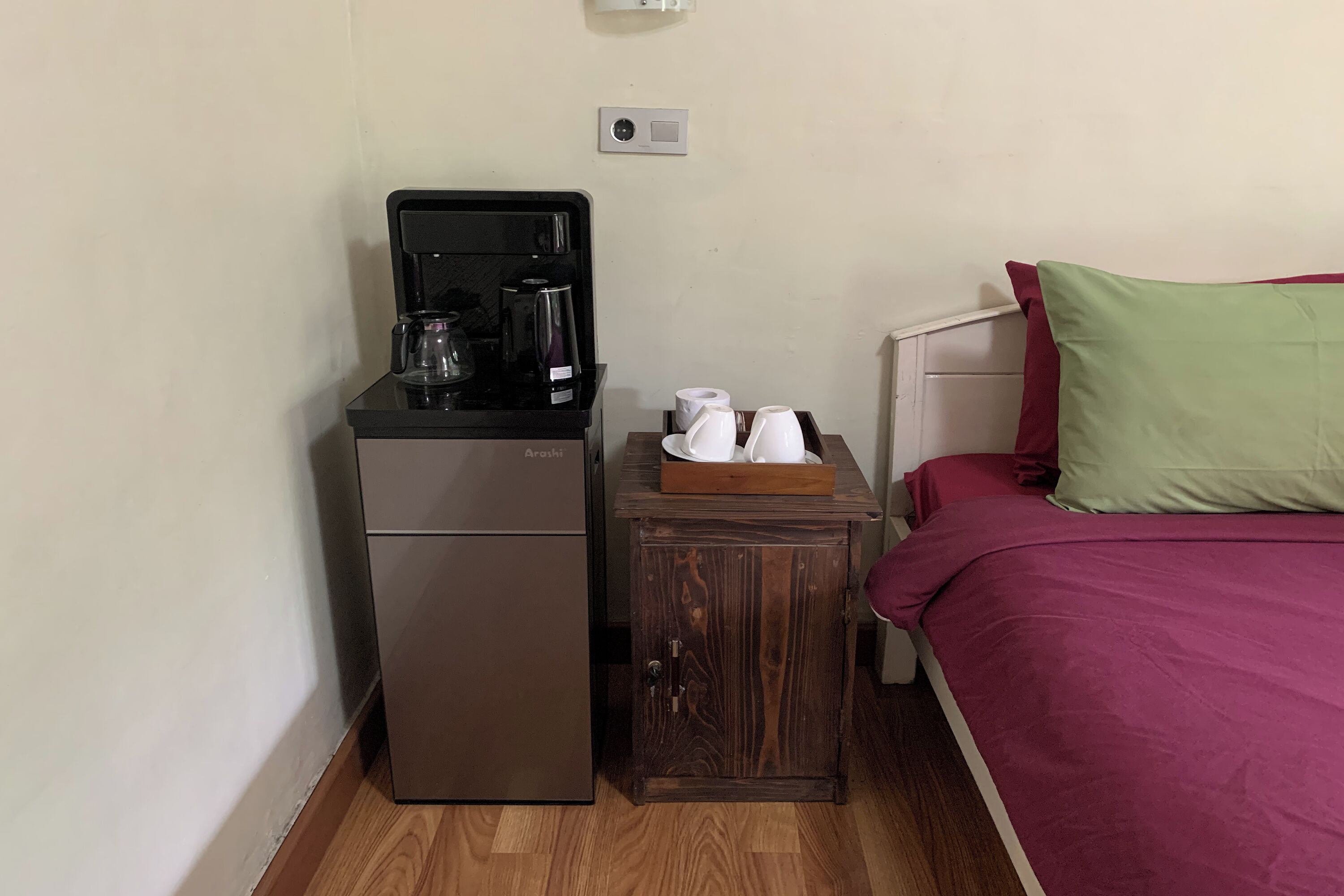 Une petite cuisine équipée comprenant une machine à café, un petit réfrigérateur et une table d’appoint en bois avec des tasses et un plateau.
