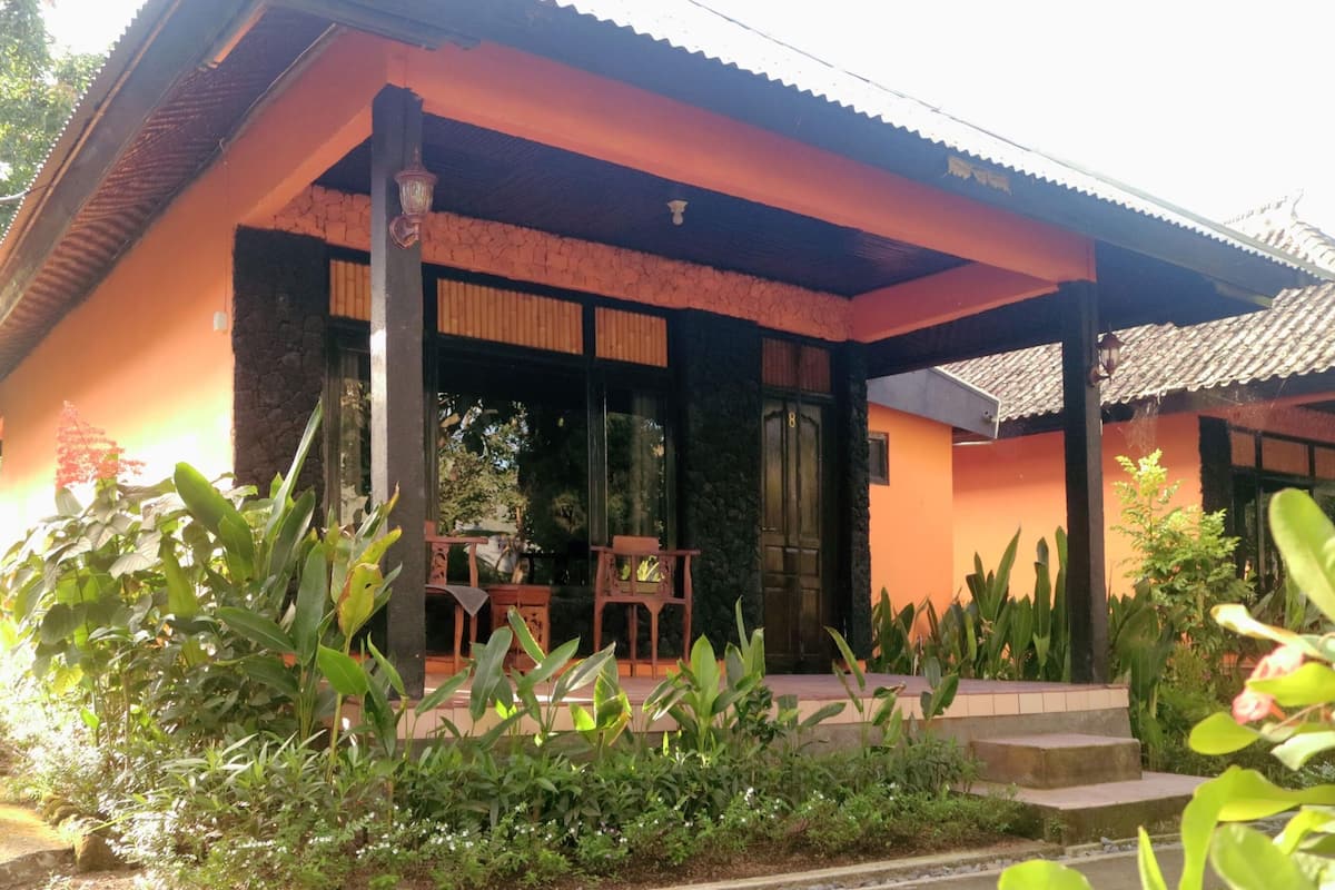Una casa con porche, ventanas amplias y un jardín con diversas plantas.