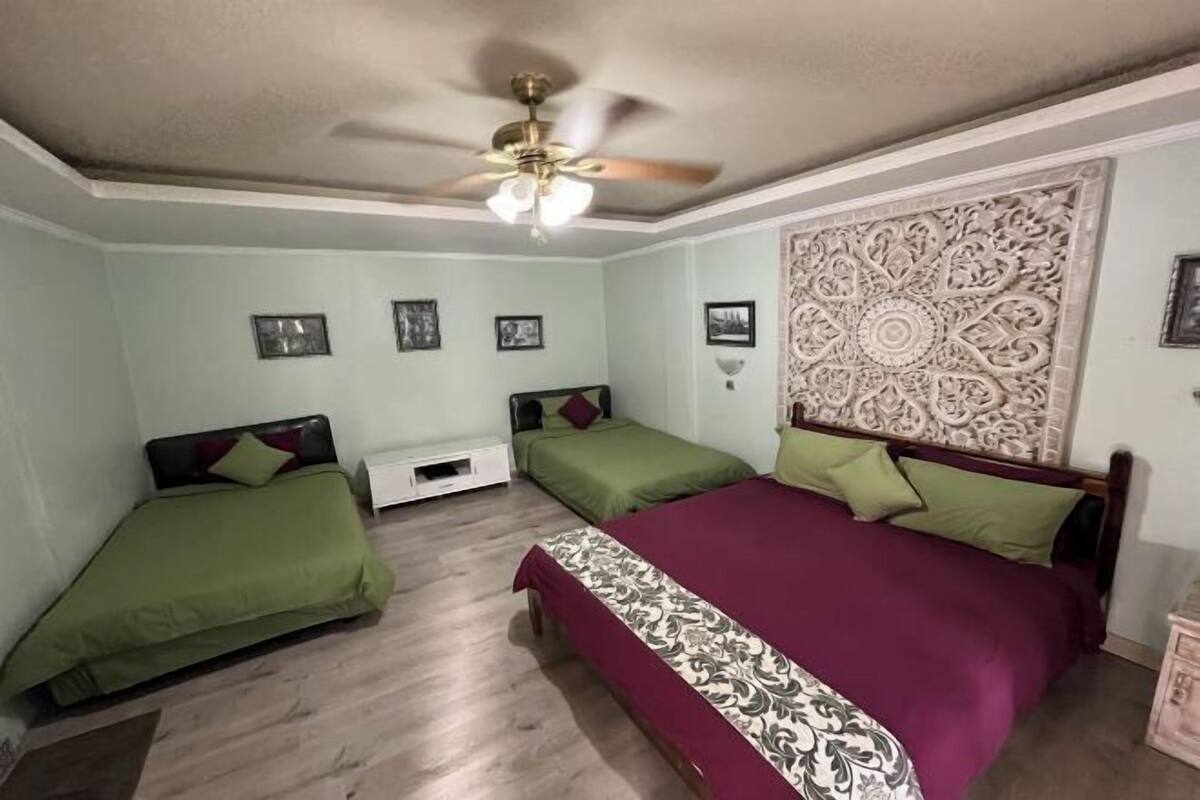 Un dormitorio con dos camas individuales, un ventilador de techo y un panel decorativo en la pared.