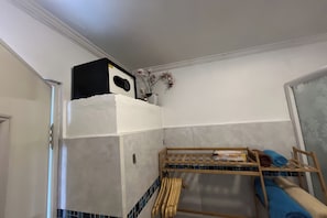 Ein kleiner, kompakter Raum mit einem Etagenbett, einem kleinen Ablagefach für Toilettenartikel und einem an der Wand befestigten Lautsprecher.