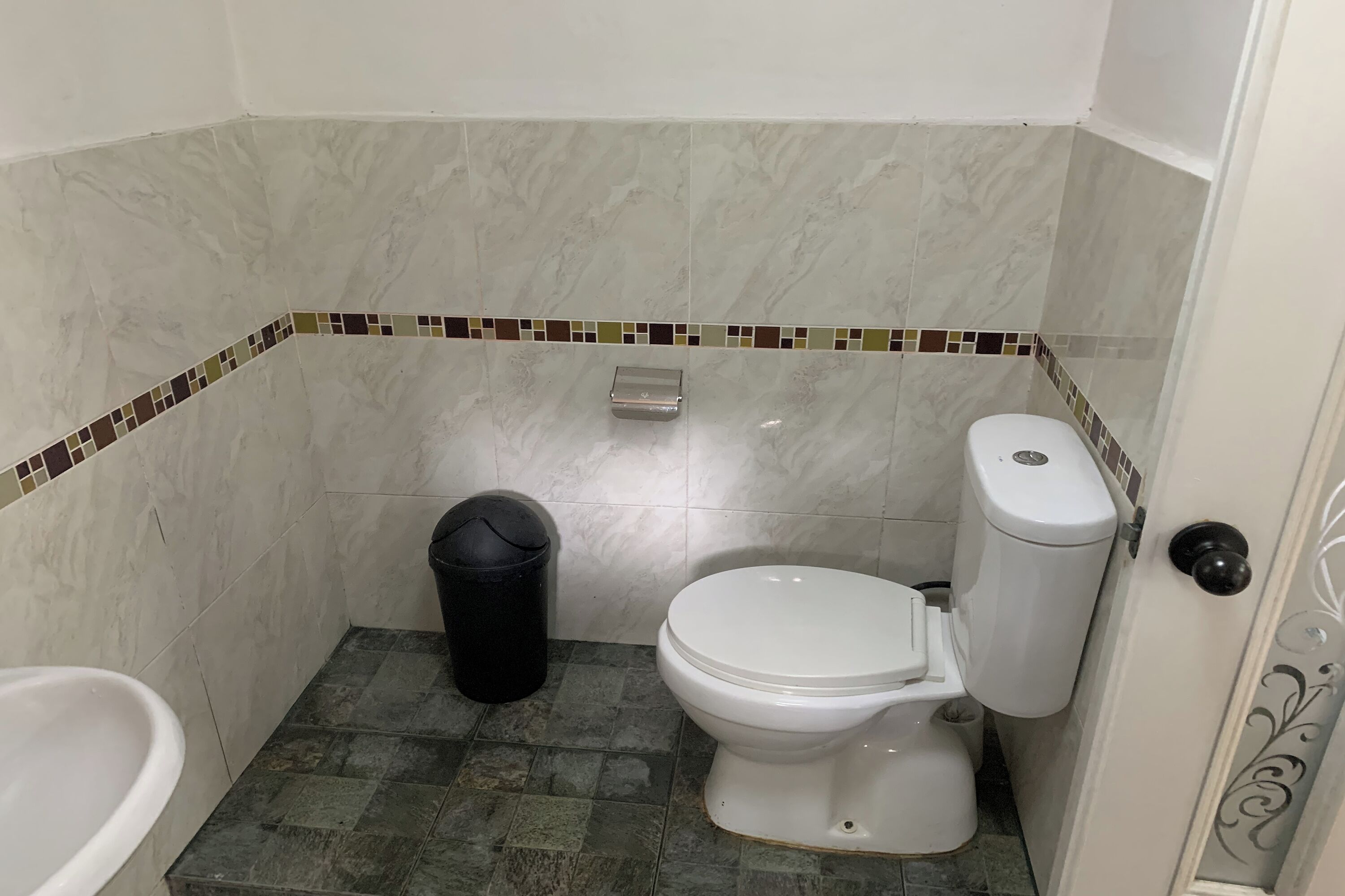 A bathroom with a toilet, a trash bin, and a bathtub.