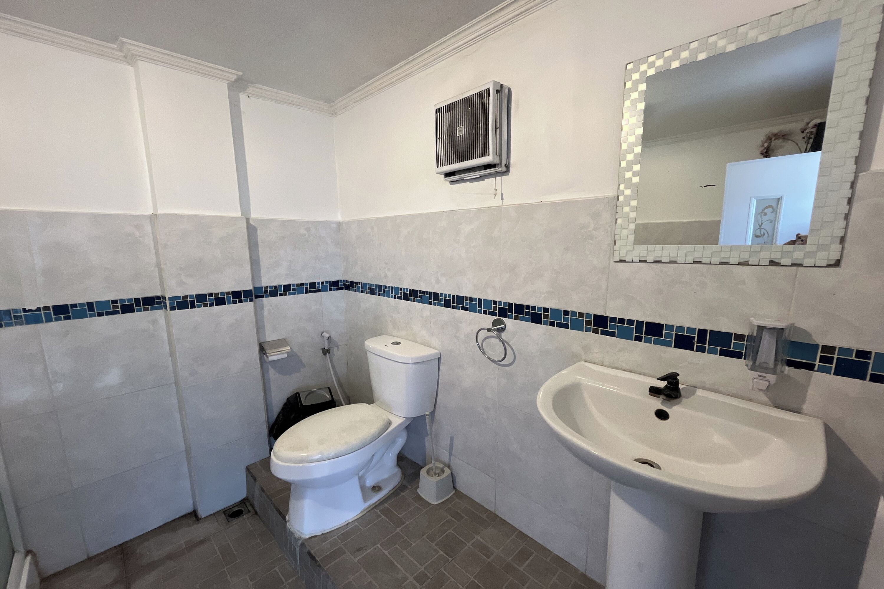 Une salle de bain avec des toilettes, un lavabo et un miroir.