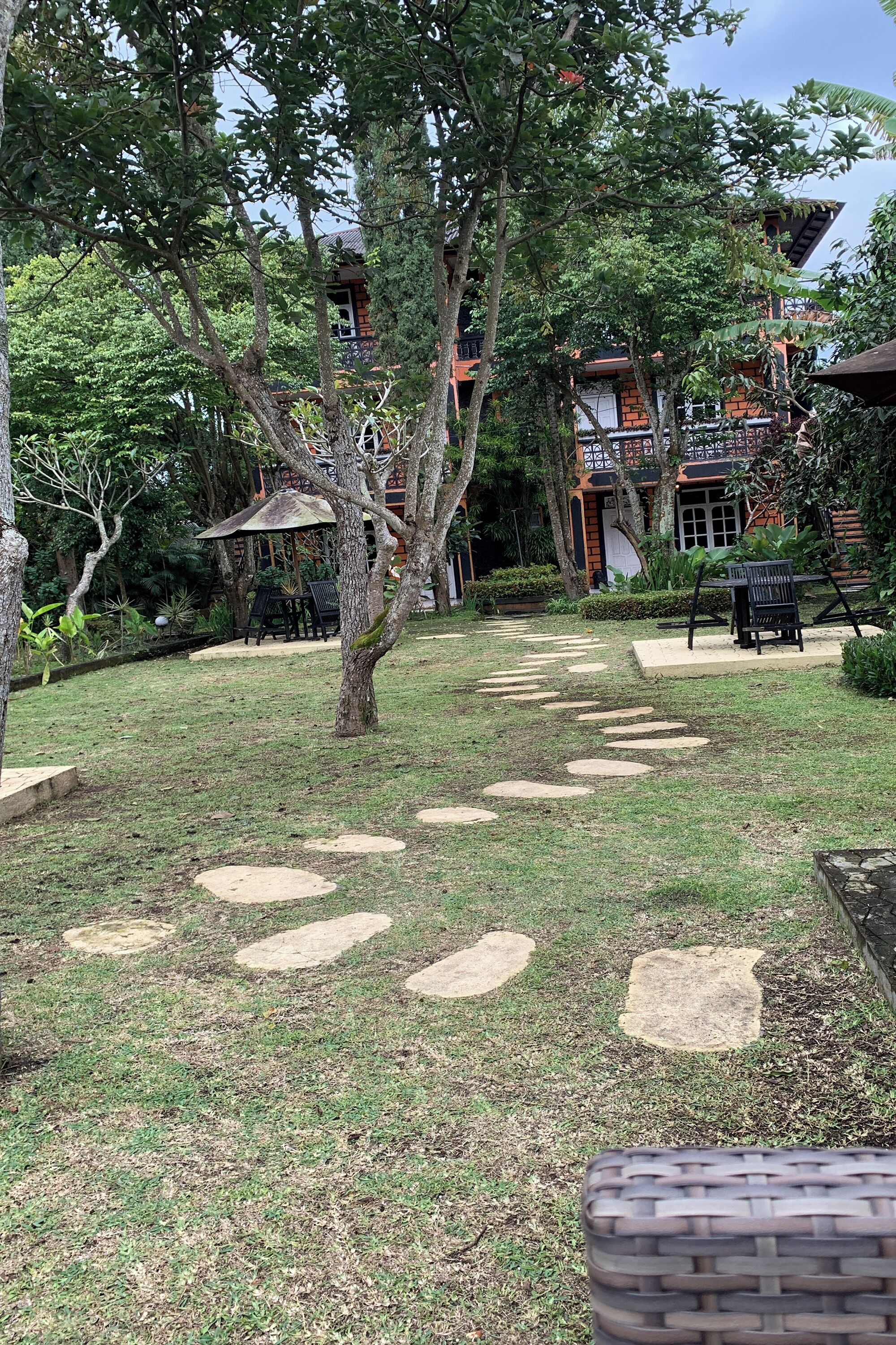 Un patio con un camino de piedra, árboles y mobiliario exterior.