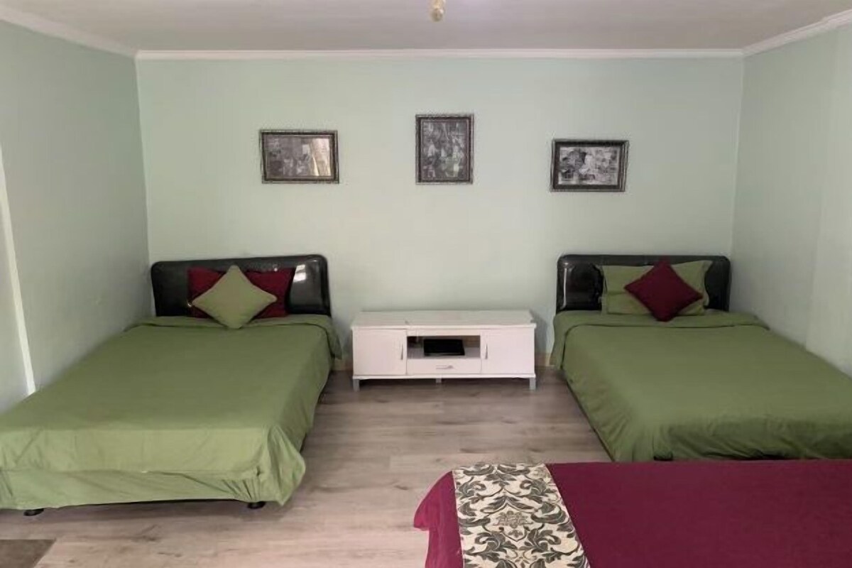 Une chambre avec deux lits simples, une petite table de chevet blanche et trois tableaux encadrés accrochés au mur.