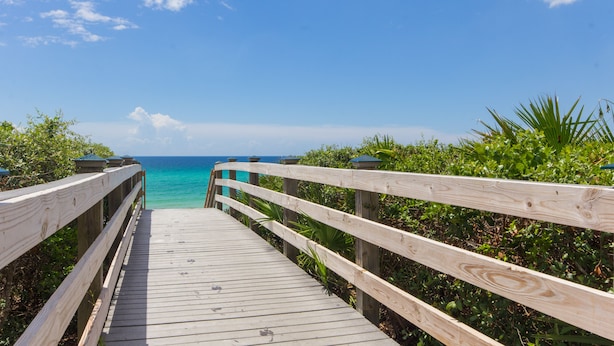 A wooden boardwalk leading to a beach with clear turquoise water.