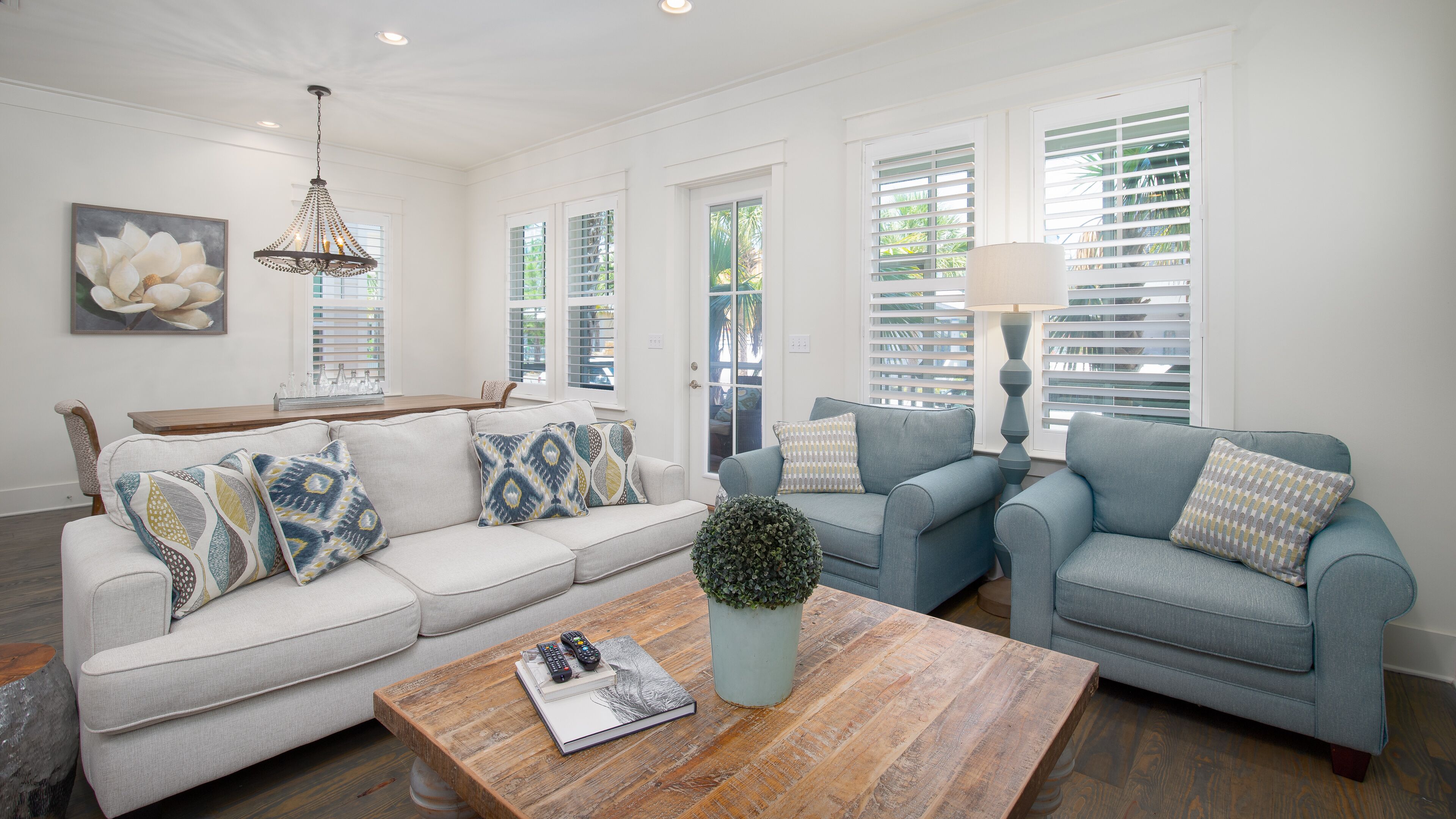 A living room with a light-colored sofa, two armchairs, a coffee table, and a potted plant.
