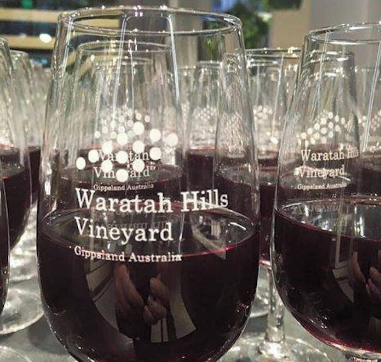 Multiple wine glasses filled with red wine, each labeled 'Waratah Hills Vineyard Gippsland Australia.'