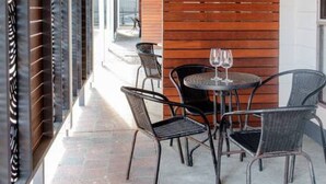 Eine Terrasse im Freien mit Holzboden, Metallstühlen und einem Tisch mit Weingläsern.